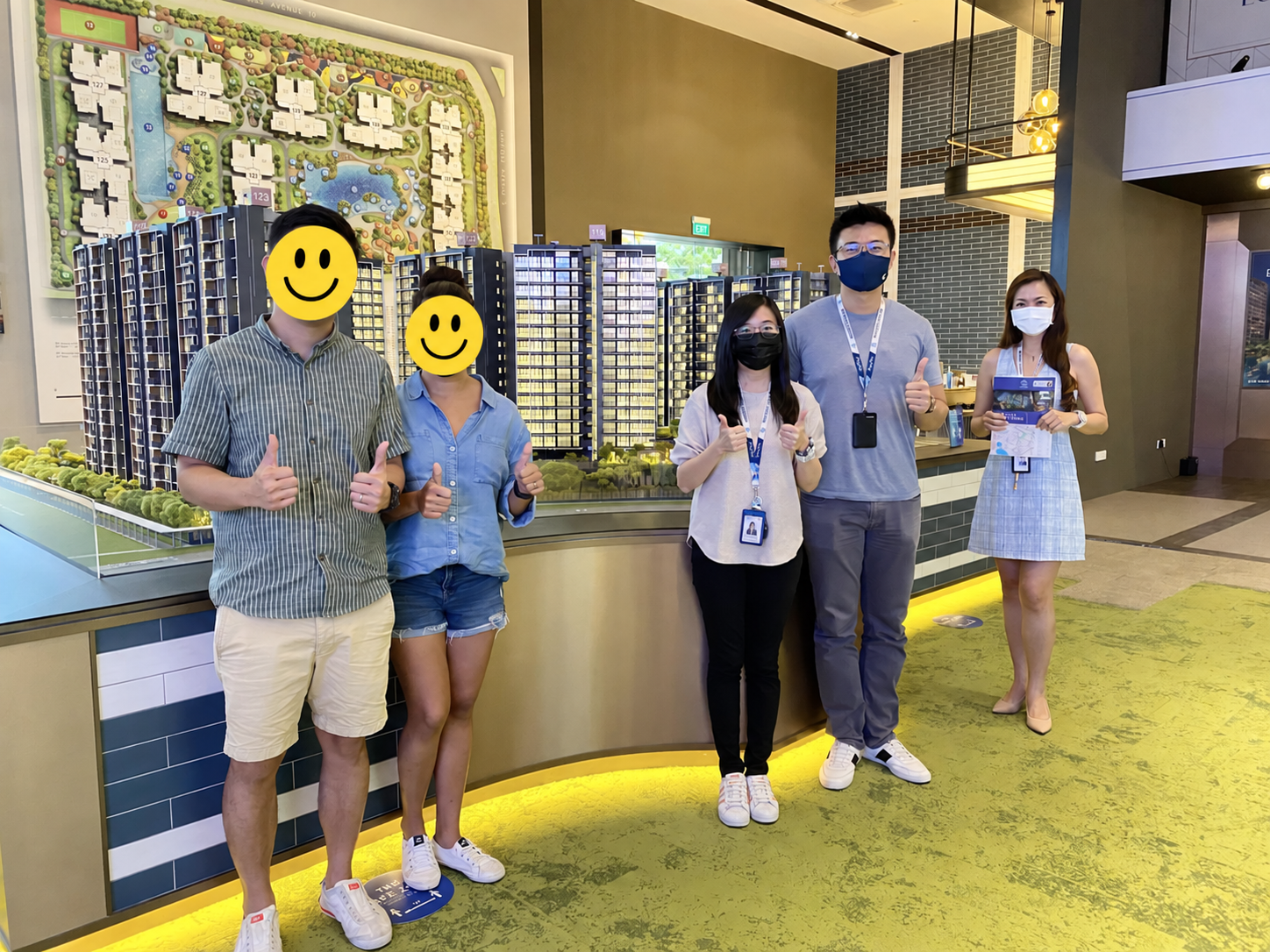 Stevenson and Celine helping clients at a property showroom, with the clients' faces covered for privacy